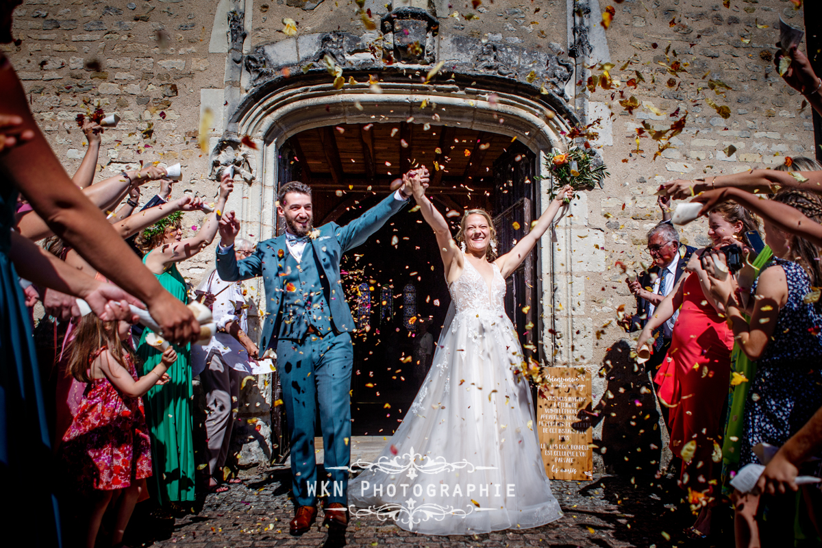 Claire et Corentin sortent de l'église sous une pluie de pétales de roses, un moment festif et magique.